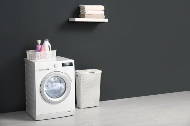Modern çamaşır makinesi, çamaşır sepeti ve banyoda havlu ile raf. Metin için alan