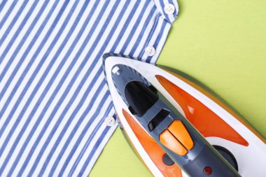 Renkli arka planda modern elektrikli demir ve gömlek, metin alanı ile üst görünüm. Çamaşırhane günü