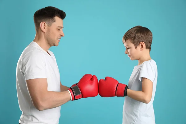 Papai e seu filho com luvas de boxe no fundo de cor — Fotografia de Stock