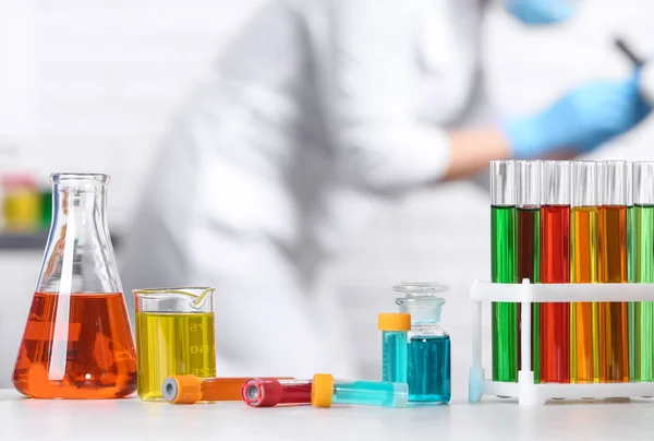 Verschiedene Gläser auf dem Tisch und Wissenschaftler im Chemielabor — Stockfoto