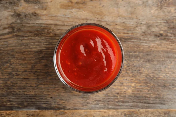 Verre de sauce tomate savoureuse sur table en bois, vue sur le dessus — Photo