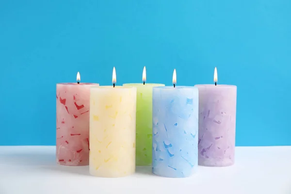 Alight świece pachnące woskiem na kolorowym tle — Zdjęcie stockowe