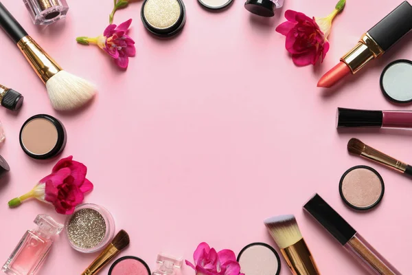 Frame gemaakt van verschillende make-up producten en bloemen op kleur achtergrond. Ruimte voor tekst — Stockfoto