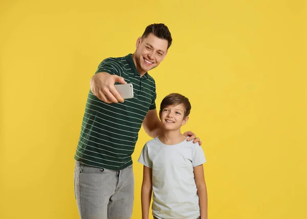 Papai e seu filho tirando selfie no fundo de cor — Fotografia de Stock