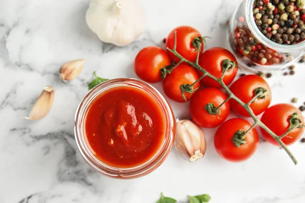 Platte lay samenstelling met jar van smakelijke tomatensaus op marmeren tafel — Stockfoto