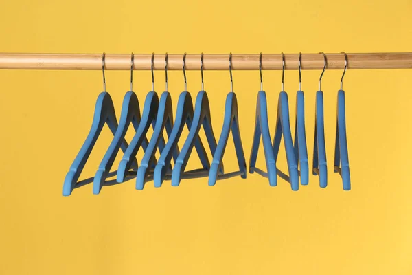 Trä rack med kläd hängare på färg bakgrund — Stockfoto