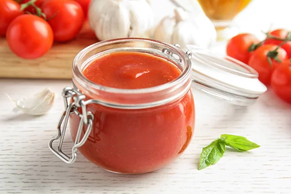 Glas mit leckerer Tomatensauce auf Holztisch, Nahaufnahme — Stockfoto