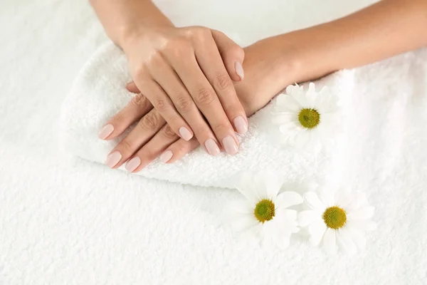 Frau mit glatten Händen und Blumen auf Handtuch, Nahaufnahme. Wellness-Behandlung — Stockfoto