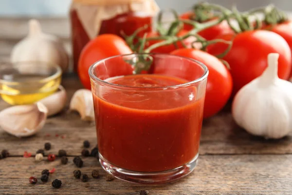 Composition avec verre de sauce tomate savoureuse sur table en bois — Photo