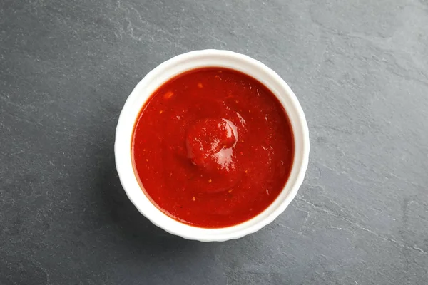 Schüssel mit leckerer Tomatensauce auf grauem Tisch, Draufsicht — Stockfoto