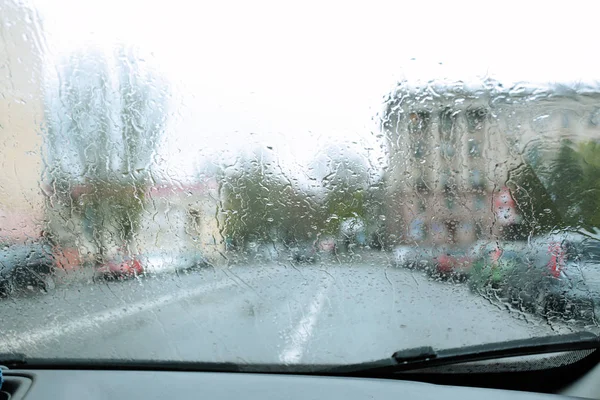 Blurred view of road through wet car window. Rainy weather — Stock Photo, Image