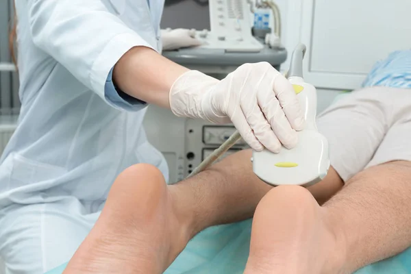 Doctor conducting ultrasound examination of patient\'s foot in clinic, closeup