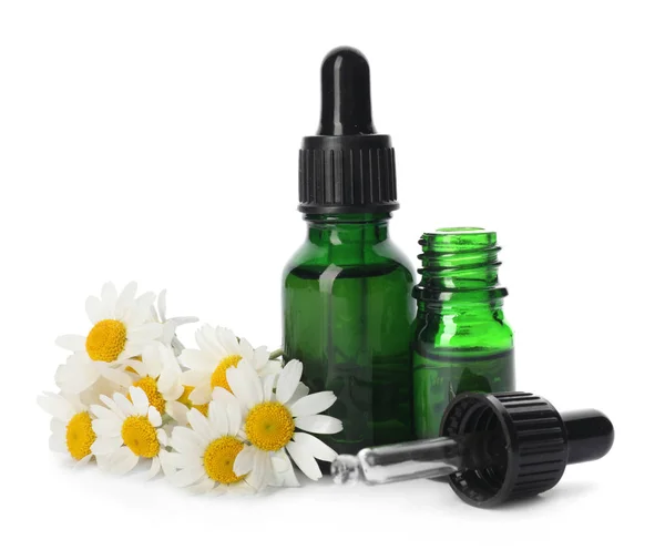 Flores de camomila e garrafas cosméticas de óleo essencial sobre fundo branco — Fotografia de Stock