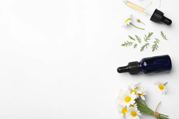 Composizione con fiori di camomilla e bottiglia cosmetica di olio essenziale su fondo bianco, vista dall'alto — Foto Stock