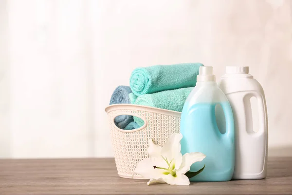 Toalhas limpas em cesta com lírio e detergentes na mesa. Espaço para texto — Fotografia de Stock