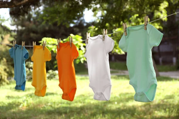 Kleurrijke baby onesies opknoping op kledinglijn buiten — Stockfoto