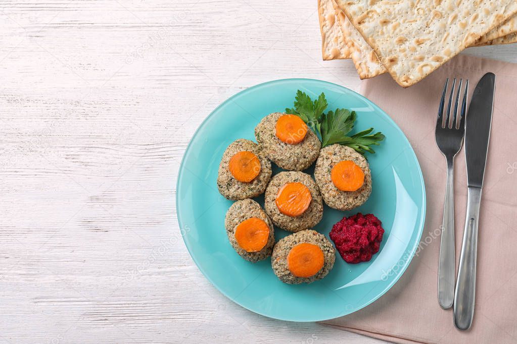 Flat lay composition with plate of traditional Passover (Pesach) gefilte fish on wooden background. Space for text