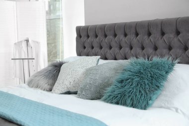 Farklı yastıklar ve hafif odada ekose ile rahat yatak. İç dekor için fikir