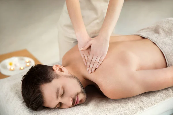 Bonito homem recebendo massagem de volta no salão de spa — Fotografia de Stock