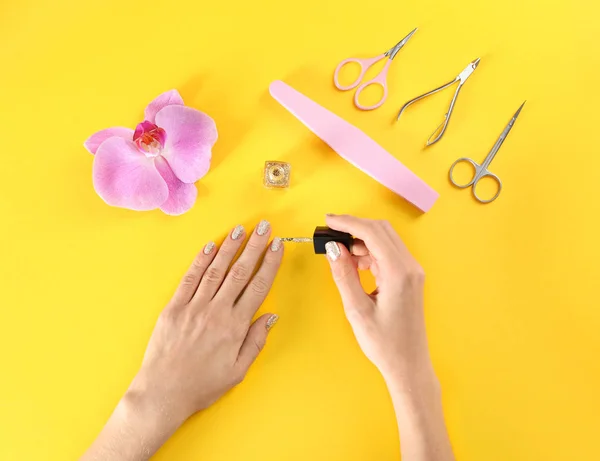 Kvinna applicera nagellack på färg bakgrunden, ovanifrån — Stockfoto