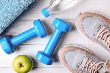 Ahşap arka plan üzerinde vinil dambıl ve spor ayakkabıları ile Düz yatıyordu kompozisyon