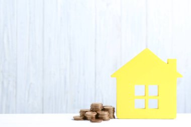 Ahşap arka plan karşı masada ev modeli ve sikkeler. Metin için alan