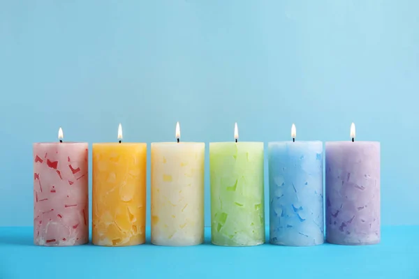 Alight scented wax candles on color background
