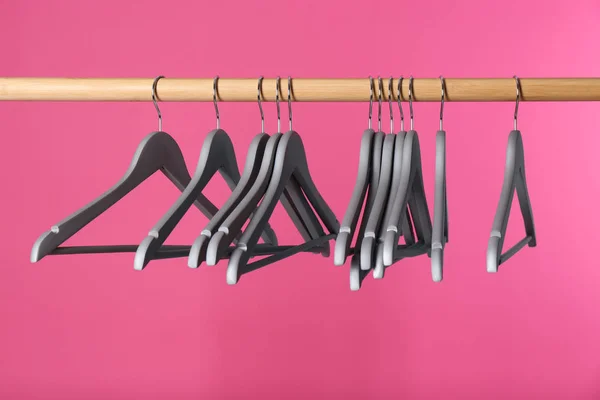 Wooden rack with clothes hangers on color background — Stock Photo, Image