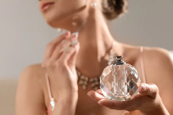 Jovem mulher aplicando perfume no fundo borrado, close-up — Fotografia de Stock