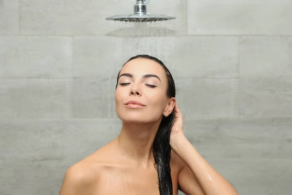 Schöne junge Frau unter der Dusche im Wellness-Center — Stockfoto