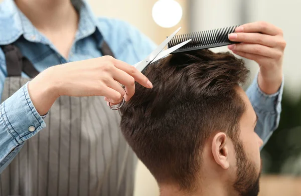 Barber making stylish haircut with professional scissors in beauty salon, closeup — Stock Photo, Image