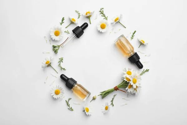 Composição com flores de camomila e garrafas cosméticas de óleo essencial sobre fundo branco, vista superior. Espaço para texto — Fotografia de Stock