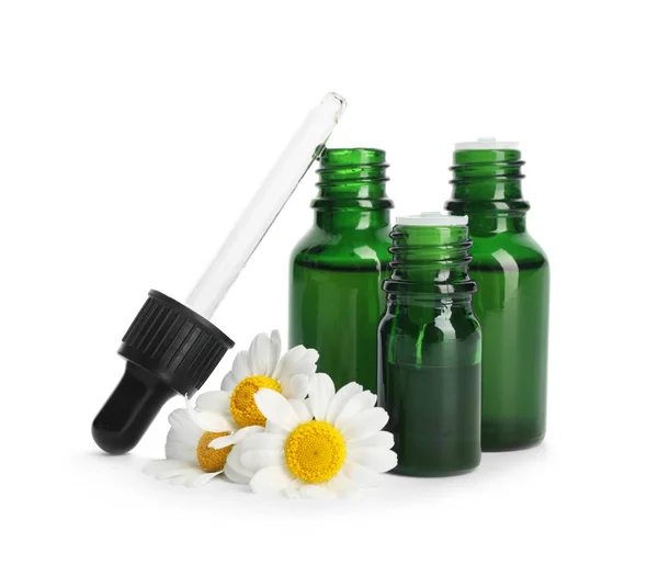 Flores de camomila e garrafas cosméticas de óleo essencial sobre fundo branco — Fotografia de Stock