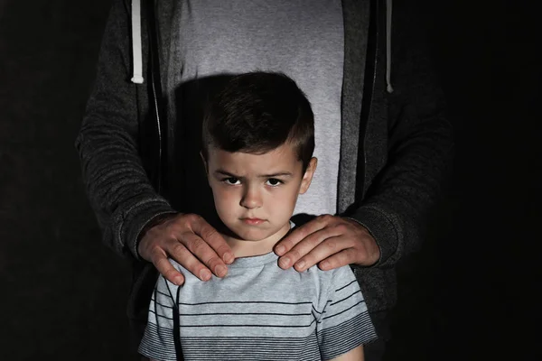 Испуганный маленький мальчик и взрослый мужчина на темном фоне. Ребенок в опасности — стоковое фото