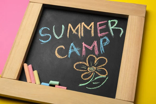 Mała tablica z tekstem Summer Camp, rysunek i kreda kije na tle koloru — Zdjęcie stockowe