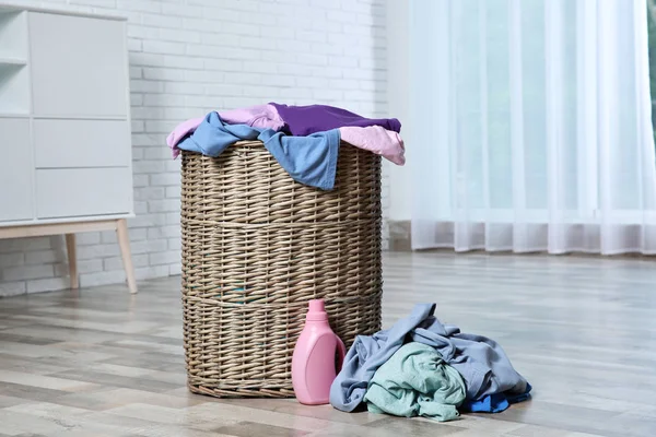 Cesta de lavandería con ropa sucia y detergente en el suelo en la habitación —  Fotos de Stock