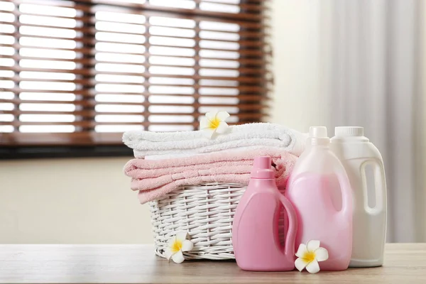 Чисті рушники в кошику з квітами і миючими засобами на столі в приміщенні. Простір для тексту — стокове фото