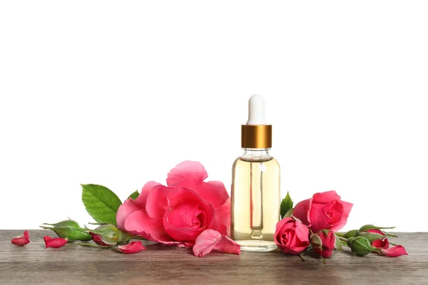 Garrafa de rosa óleo essencial e flores na mesa, fundo branco — Fotografia de Stock