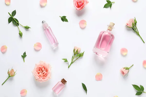 Komposisi dengan minyak mawar esensial dan bunga pada latar belakang putih, atas pandangan — Stok Foto