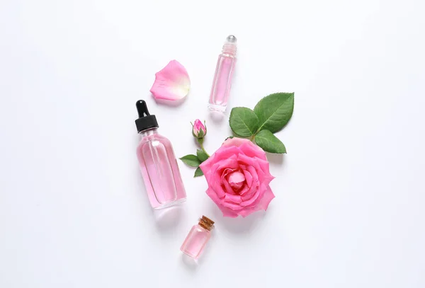 Composição com óleo essencial de rosa e flores sobre fundo branco, vista superior — Fotografia de Stock