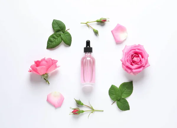 Összetétel Rózsa illóolajjal és virágokkal fehér alapon, felülnézet — Stock Fotó