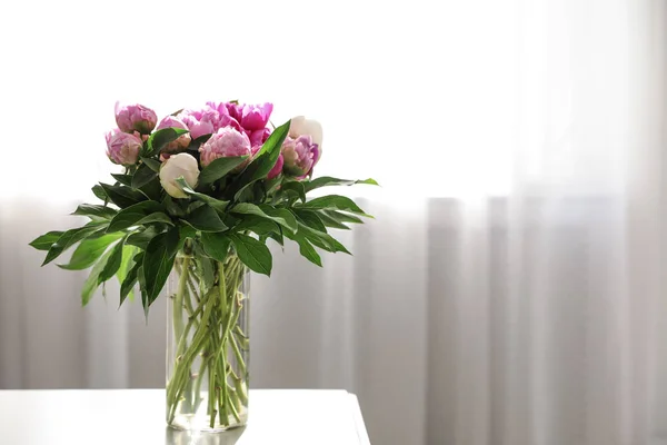 Florero con ramo de hermosas peonías en la mesa en la habitación, espacio para el texto —  Fotos de Stock