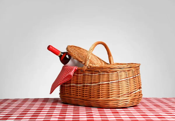 Корзина для пикника с бутылкой вина на клетчатой скатерти на белом фоне — стоковое фото