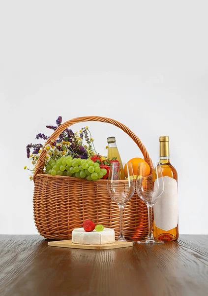 Piknik kosár borral és termékek fából készült asztal fehér háttérrel — Stock Fotó