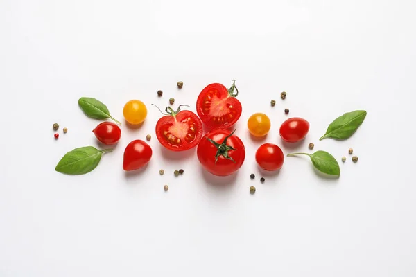 Composición con tomates cherry maduros y hojas de albahaca sobre fondo blanco, vista superior — Foto de Stock
