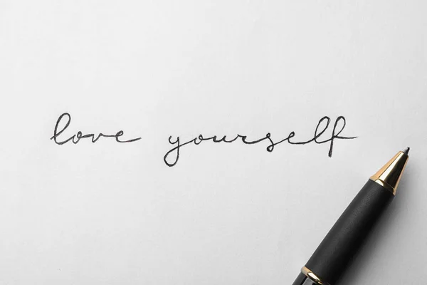 Написані слова "LOVE YOURSELF" і ручка на білому тлі, вид зверху — стокове фото