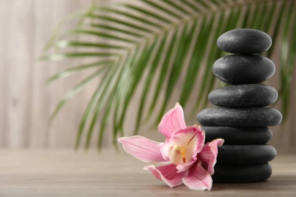 Stapel schwarzer Wellness-Steine mit Blume auf Holzgrund. Raum für Text — Stockfoto