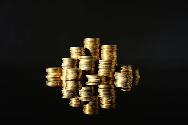 Många högar av mynt på spegelyta mot svart bakgrund — Stockfoto