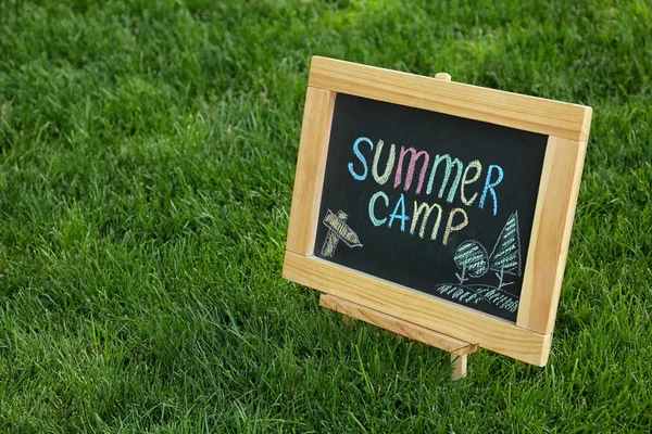 Tafel mit Text-Sommerlager und Zeichnungen auf grünem Gras. Raum für Text — Stockfoto