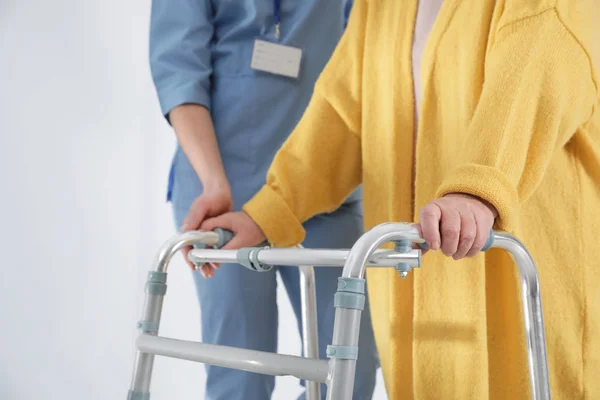Медсестра ассистирует старшей женщине с Уолкером в больнице, крупным планом — стоковое фото